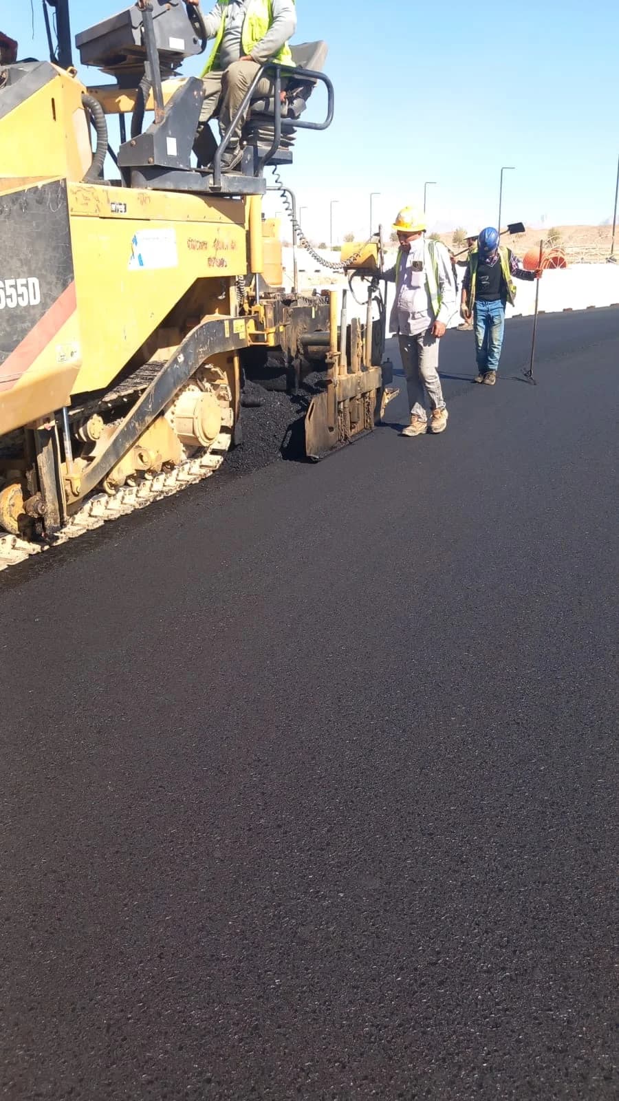 Paving crew and equipment working on a blacktop road surface.