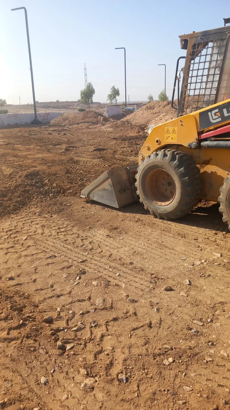 Close view of loader bucket and tire during road site preparation.