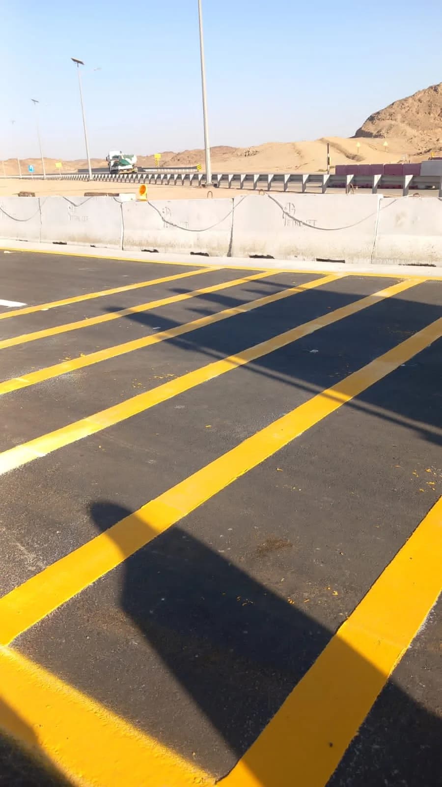Fresh yellow road marking lines on a completed asphalt surface.