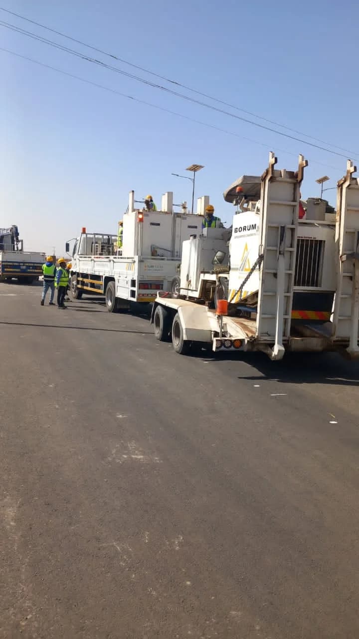 Roadwork service trucks and equipment positioned on an asphalt project site.