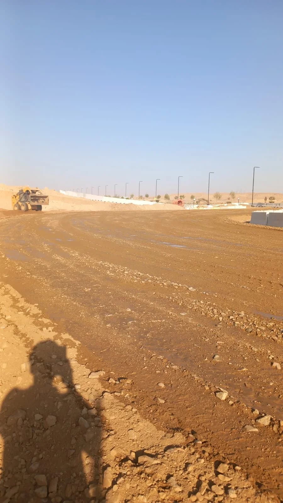 Road formation area with water and grading preparation before surfacing.